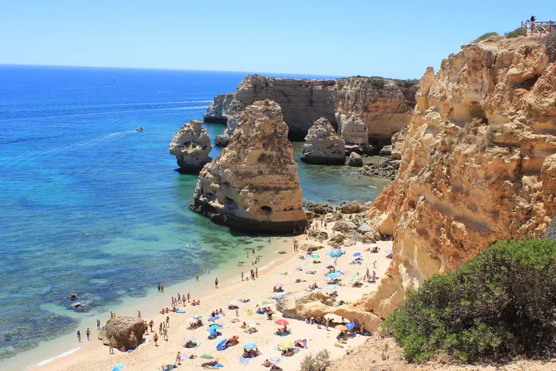 Praia da Marinha seen from the cliffs, with rock stacks, clear blue water and a sandy beach