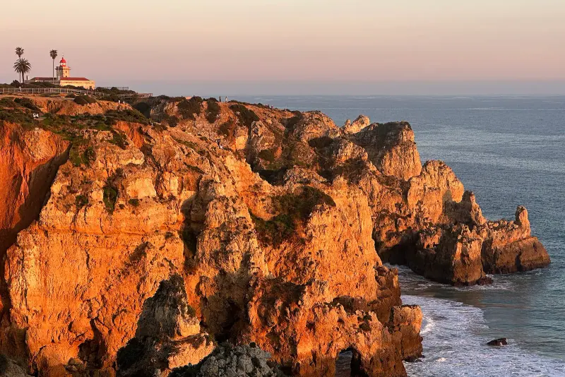 Golden sandstone cliffs and a lighthouse at Ponta da Piedade near Lagos glowing at sunset