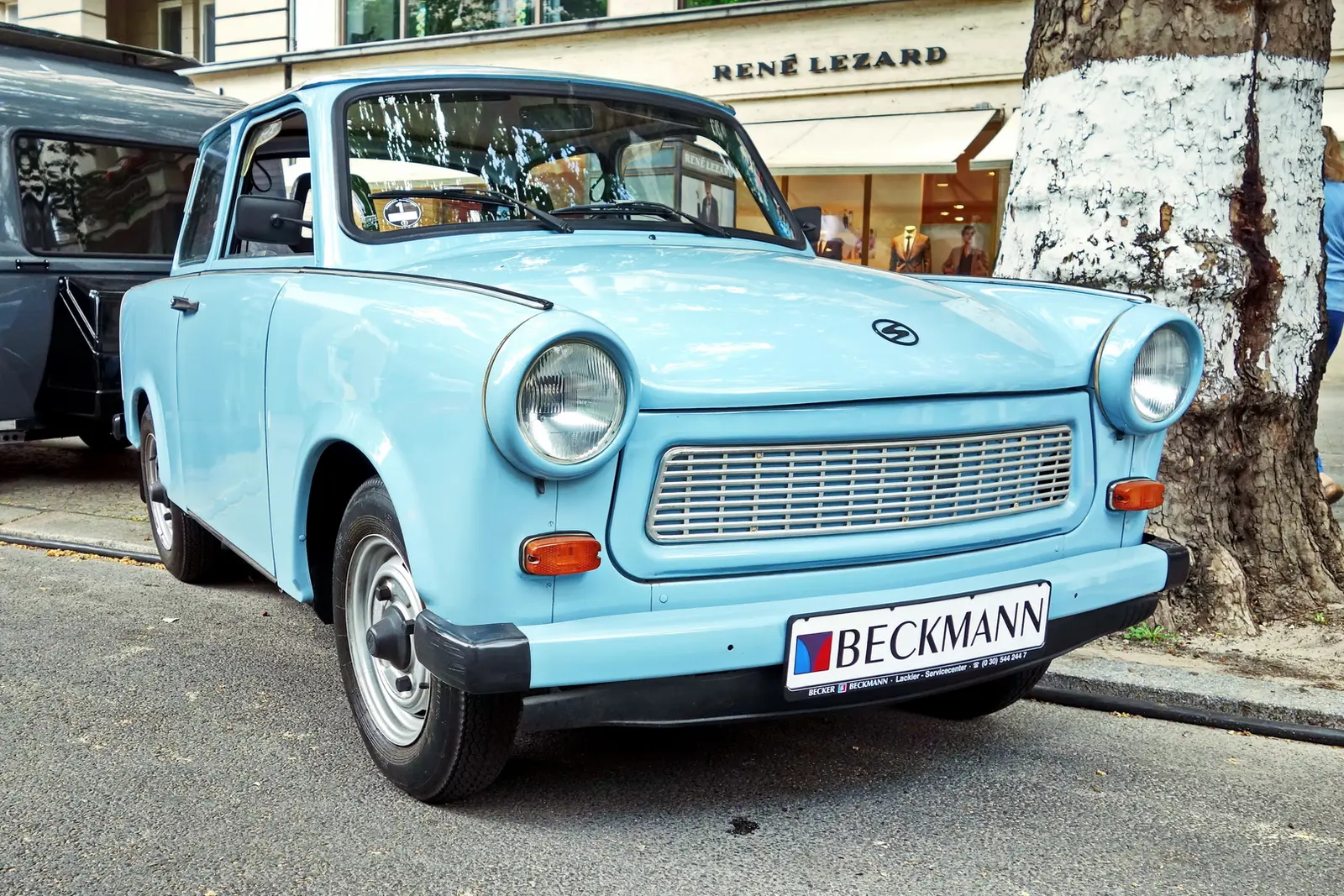 A Trabant parked beside a Berlin Wall fragment