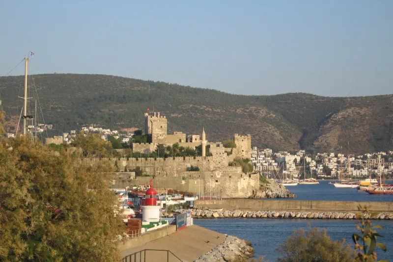 Bodrum Castle rising above the harbor and town with hills behind and boats at the quay