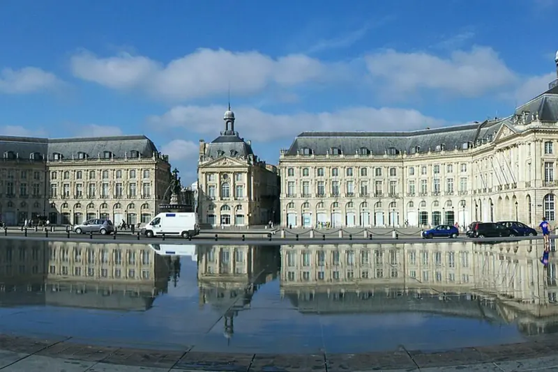 The Miroir d'eau reflecting Place de la Bourse under a blue sky
