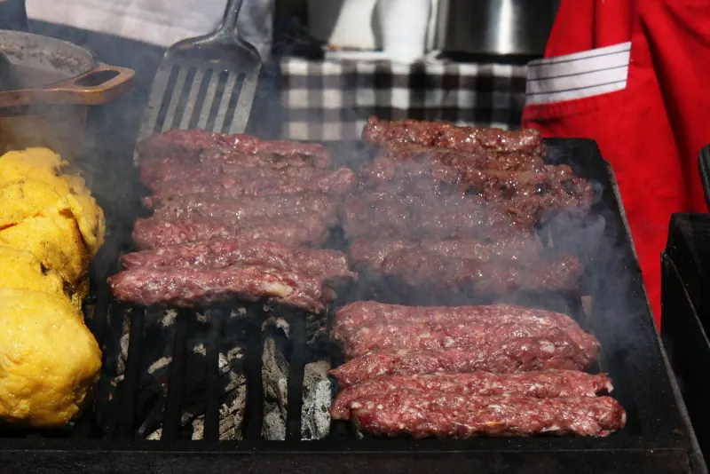 Mici, Romania's grilled minced-meat rolls, on the grill