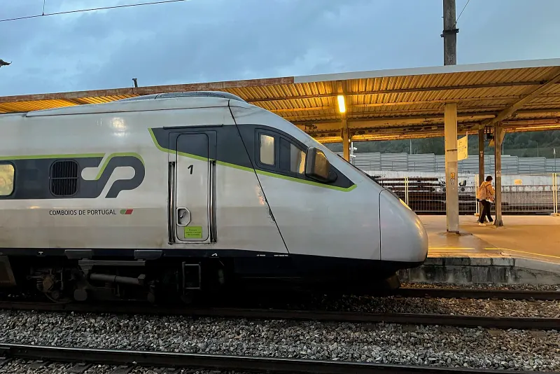 An Alfa Pendular train at a Coimbra-B platform under the evening canopy