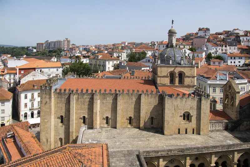 Aerial view of Se Velha's crenellated walls and cloister rising over the old town rooftops of Coimbra