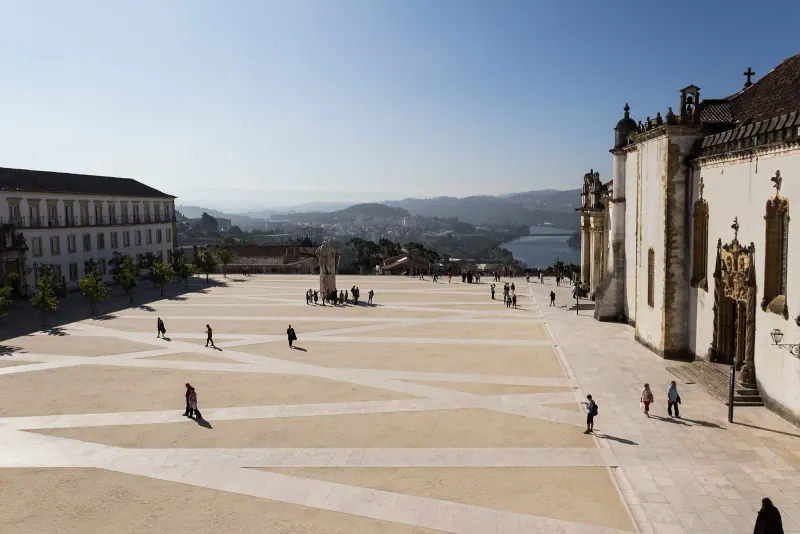 The Paço das Escolas courtyard at Coimbra University with the Joanina chapel facade and the Mondego river beyond