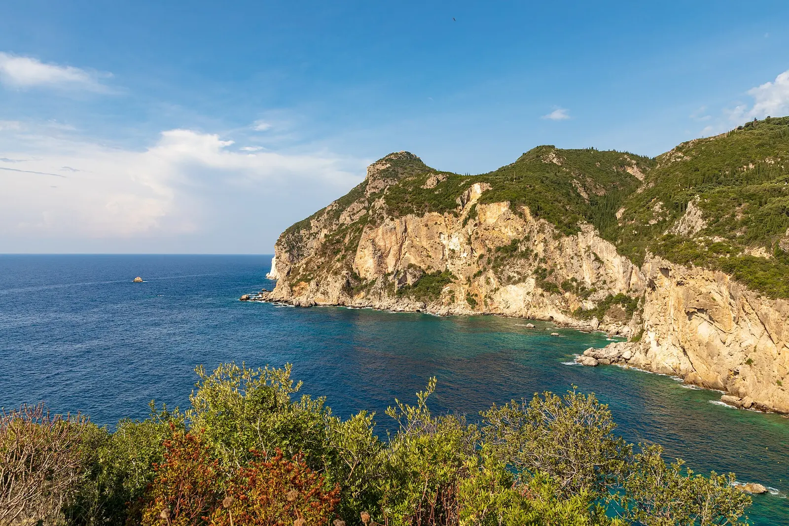 Aerial of a green headland over a turquoise bay