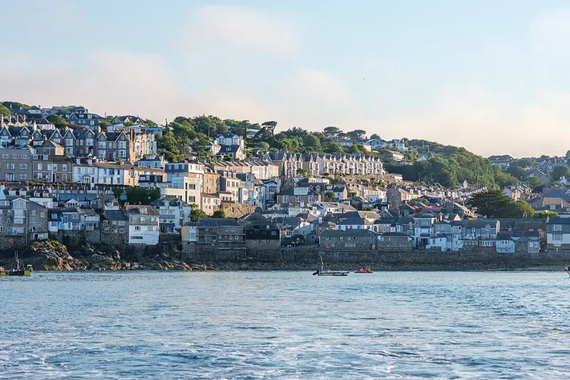 Hillside houses of St Ives seen across the water from the harbor on a clear July day