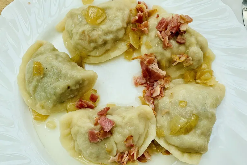 Plate of pierogi topped with bacon bits