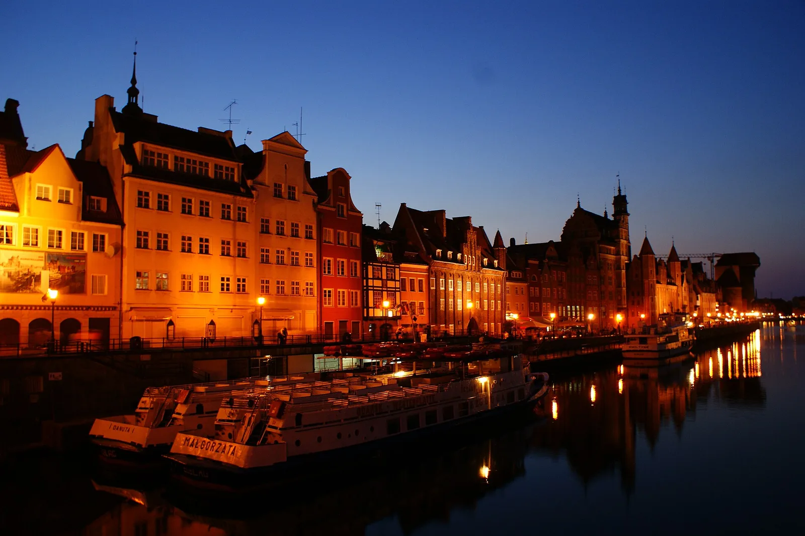 Lit gabled facades reflected in the Motlawa river at night, Gdansk