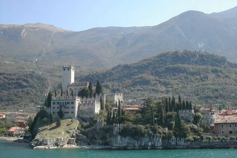 Malcesine castle on a rocky headland above the lake with mountains rising behind