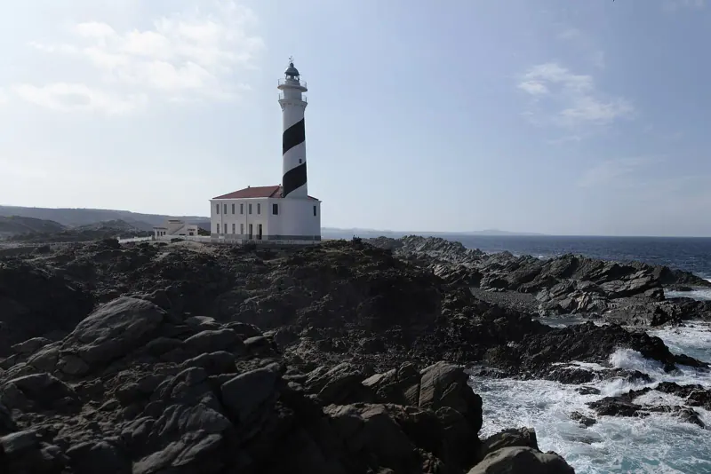 The white Favaritx lighthouse on Menorca's slate-black north coast