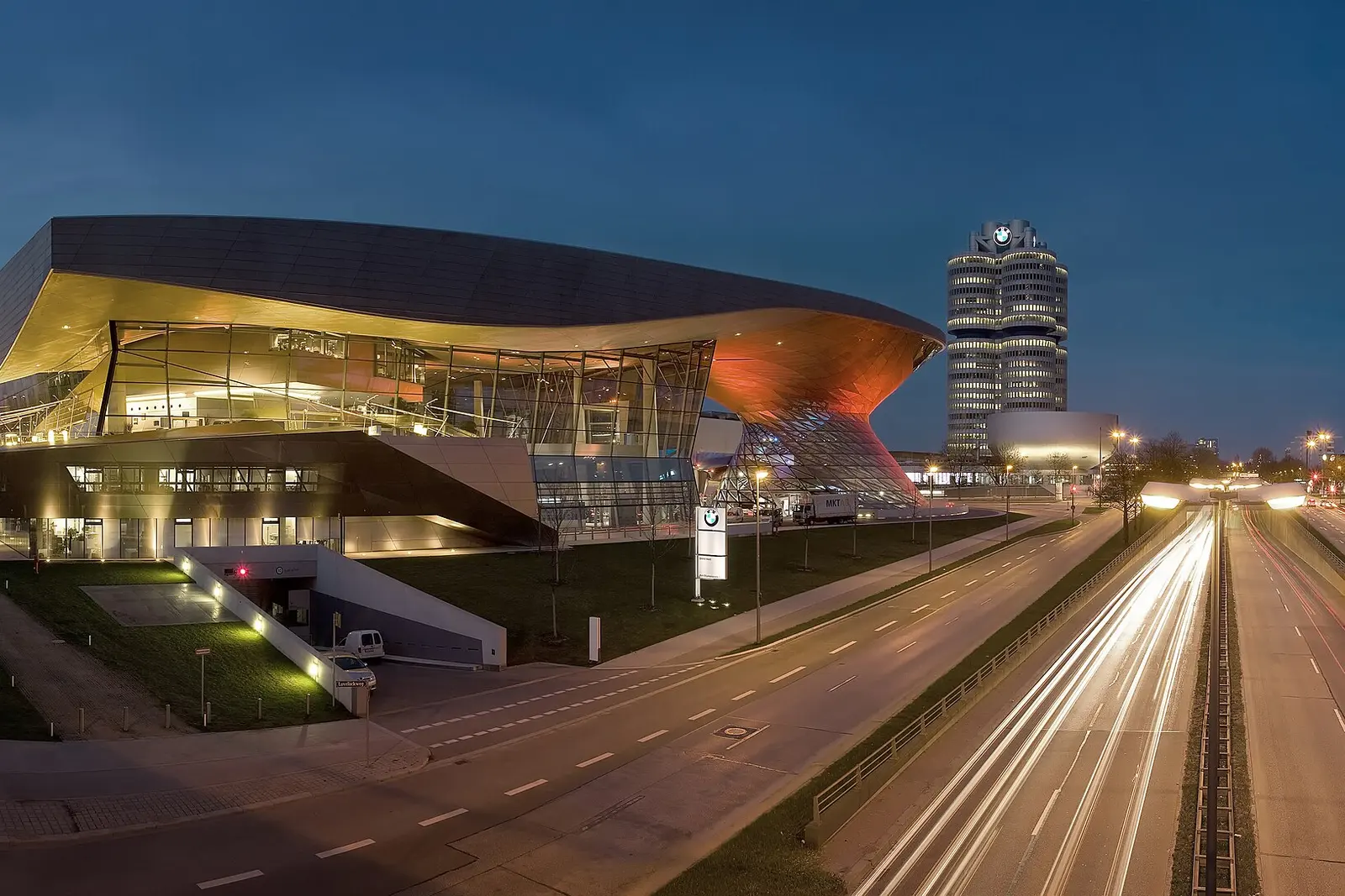 BMW Welt lit up at night beside a Munich road