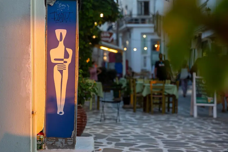Taverna tables spilling onto a Mykonos lane at dusk