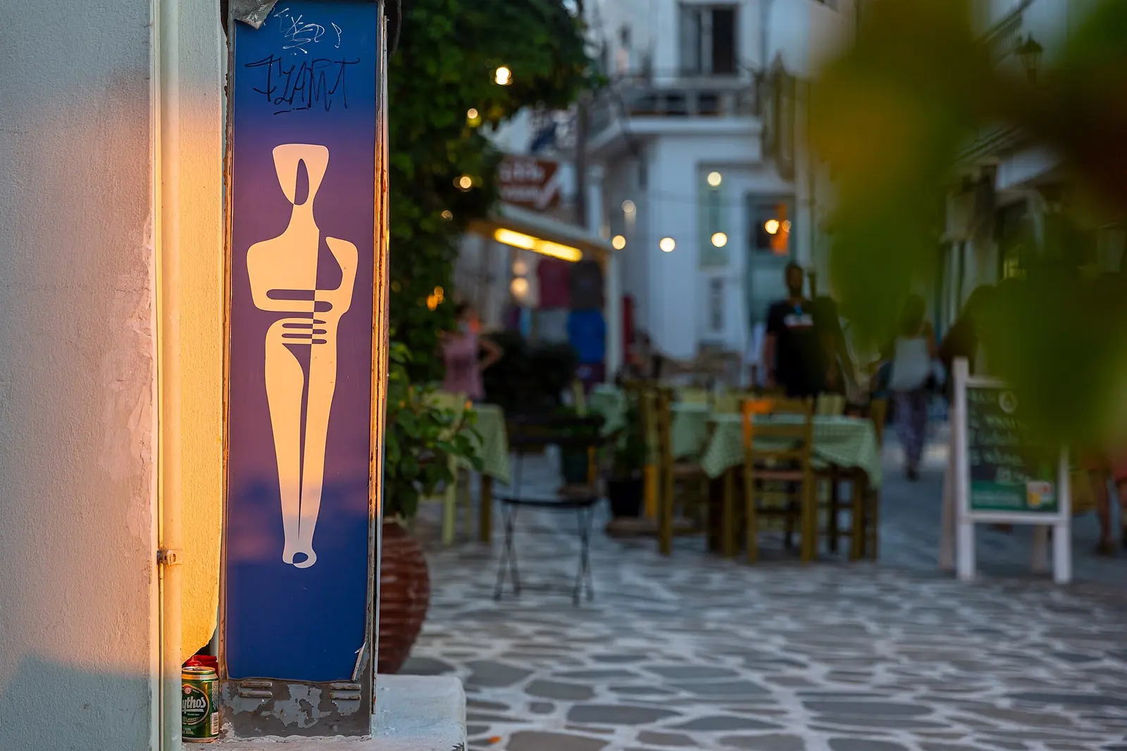 Taverna tables spilling onto a Mykonos lane at dusk