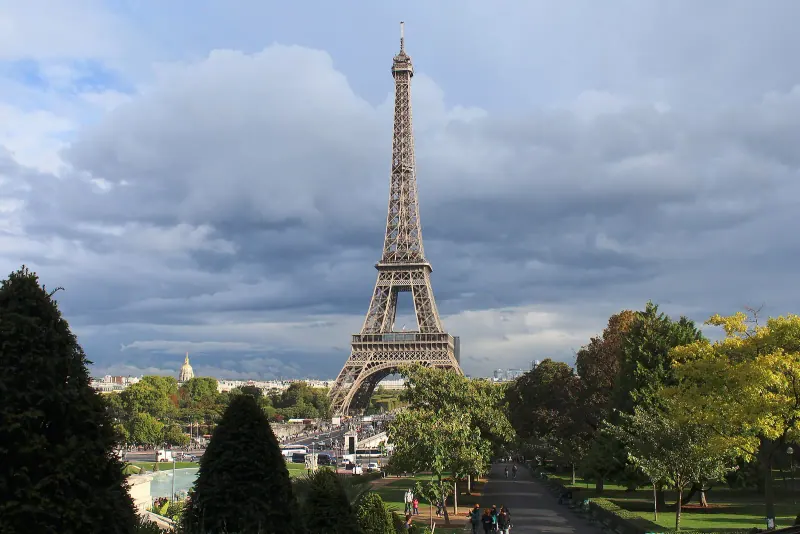 The Eiffel Tower above the trees on a cloudy day