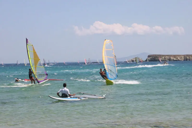 Windsurfers with colorful sails riding the choppy turquoise water off Golden Beach on a windy day