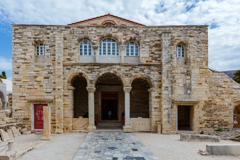 Stone facade and arched porch of the Panagia Ekatontapiliani church in Parikia on a sunny day