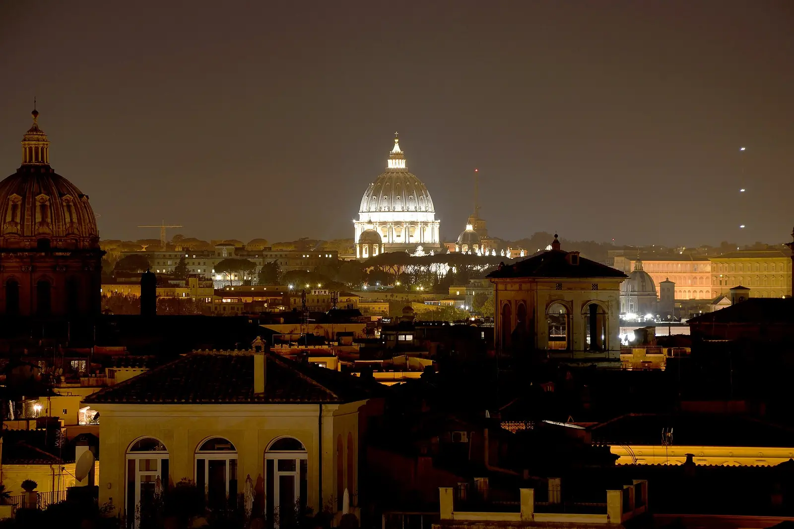 Rome's rooftops at night with the dome of St. Peter's lit up