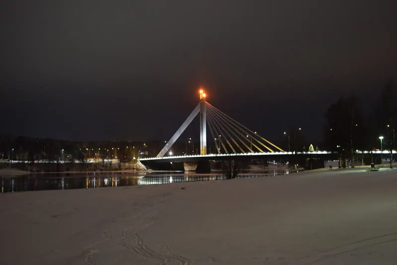 The Lumberjack Candle Bridge over the frozen river in Rovaniemi at dusk