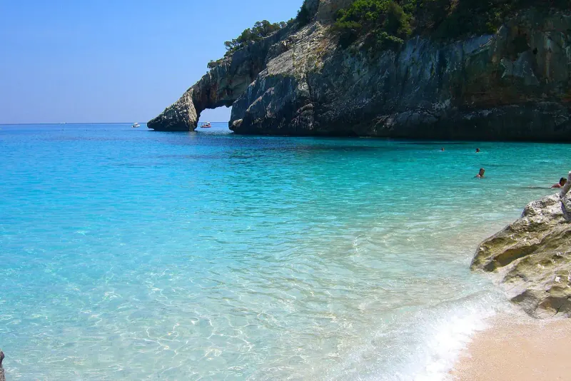 Clear turquoise water and a rock arch at the white pebble beach of Cala Goloritze in Sardinia