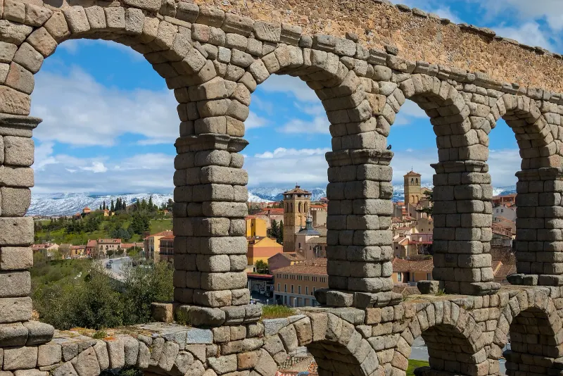 Low-angle view of the Segovia aqueduct arches against a blue sky