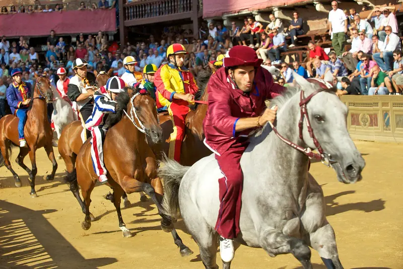 Horses and riders racing around Piazza del Campo during the Palio