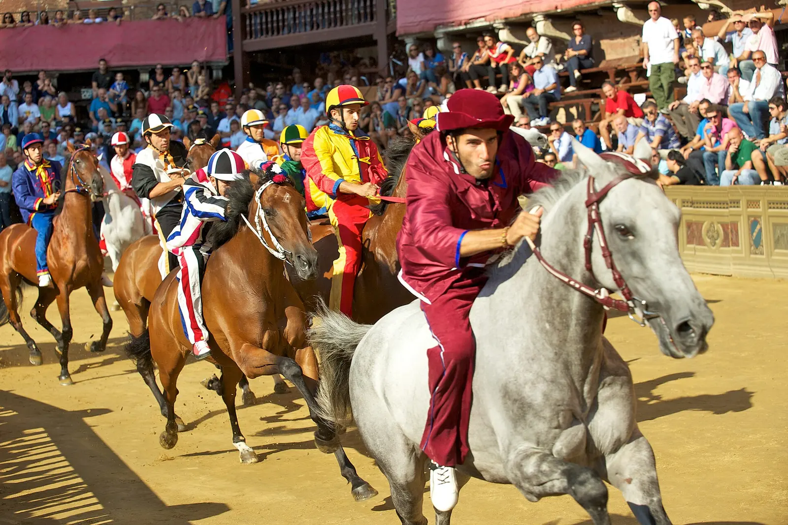 Horses and riders racing around Piazza del Campo during the Palio
