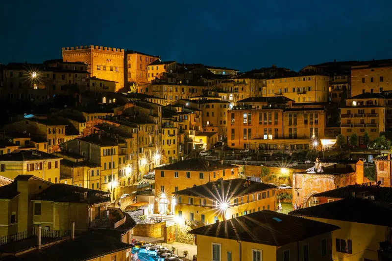 Siena's lit streets and the Torre del Mangia at dusk