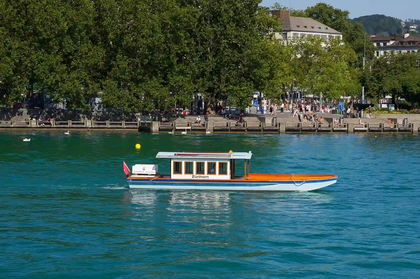A small cruise boat on turquoise Lake Zurich
